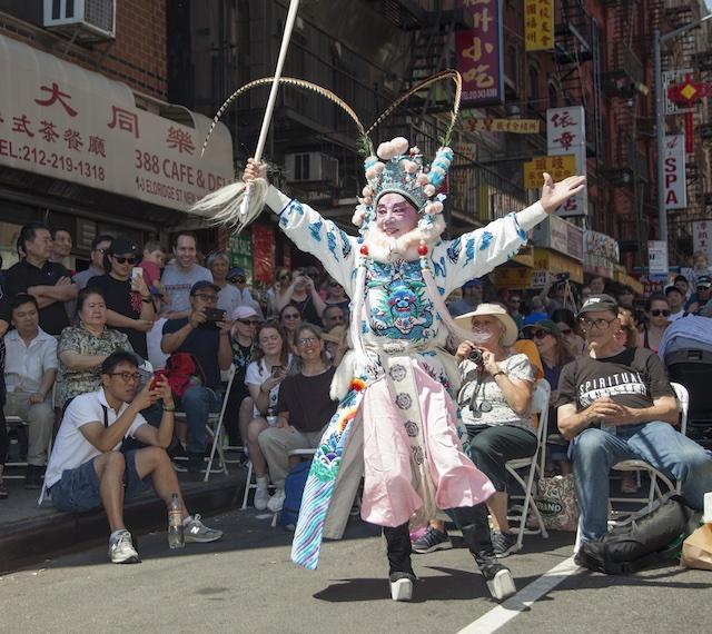 Man in an elaborate costume performing in a city street festival
