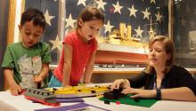 Woman with two children at a table buildig lego ships