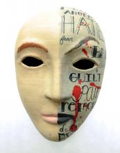 A paper mache mask painted with the words 'hate,' 'guilt,' and 'remorse.'