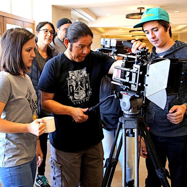 Two men and one woman filmmakers setting up an indoor camera shoot