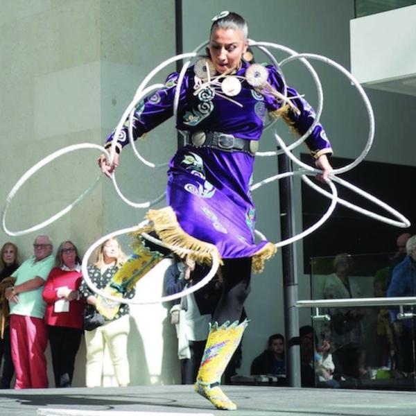 Native American hoop dancer in full costume performing on stage