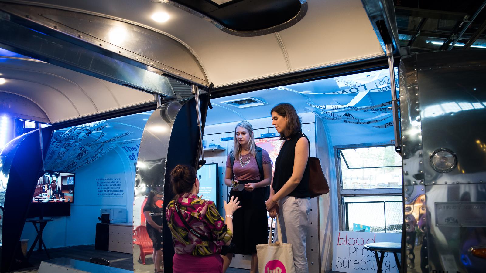 People explore a design exhibit housed in an Airstream trailer